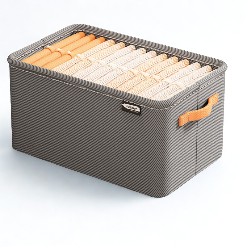 Gray storage box with handles containing rolled-up clothes on a white background