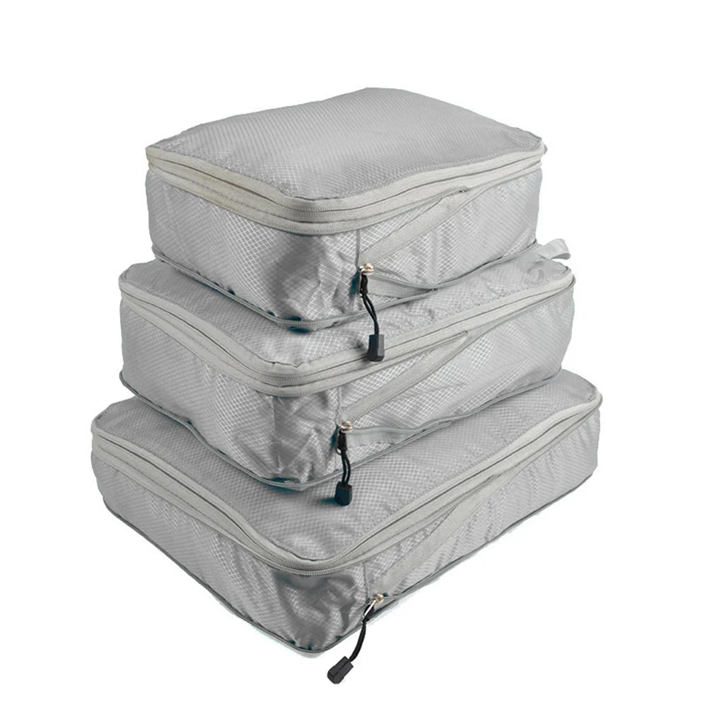 Set of three compression packing bags in black, with additional colors shown in blue and gray. Each bag has a zipper closure and a mesh side panel.