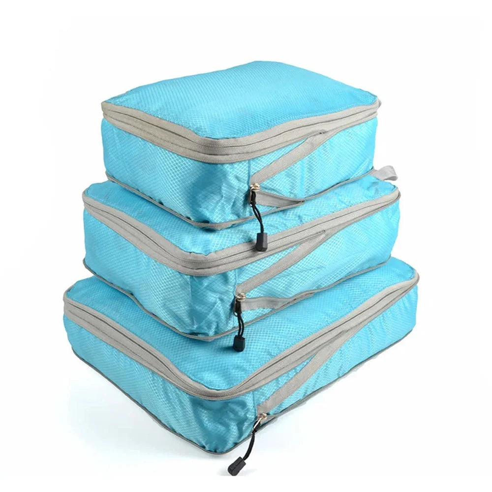 Set of three compression packing bags in black, with additional colors shown in blue and gray. Each bag has a zipper closure and a mesh side panel.