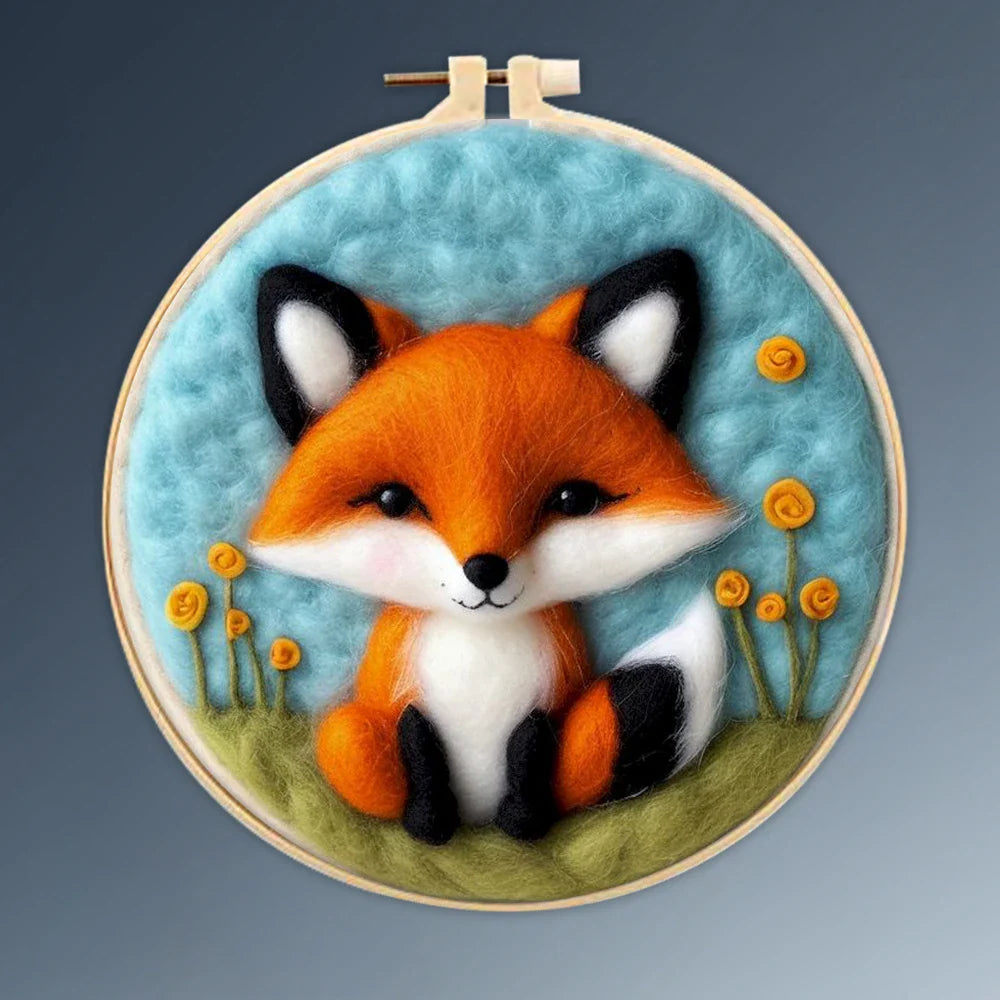 A person's hands holding a DIY felting kit with a pre-printed felt cloth depicting a white cat with orange spots, surrounded by colorful wool in the background.