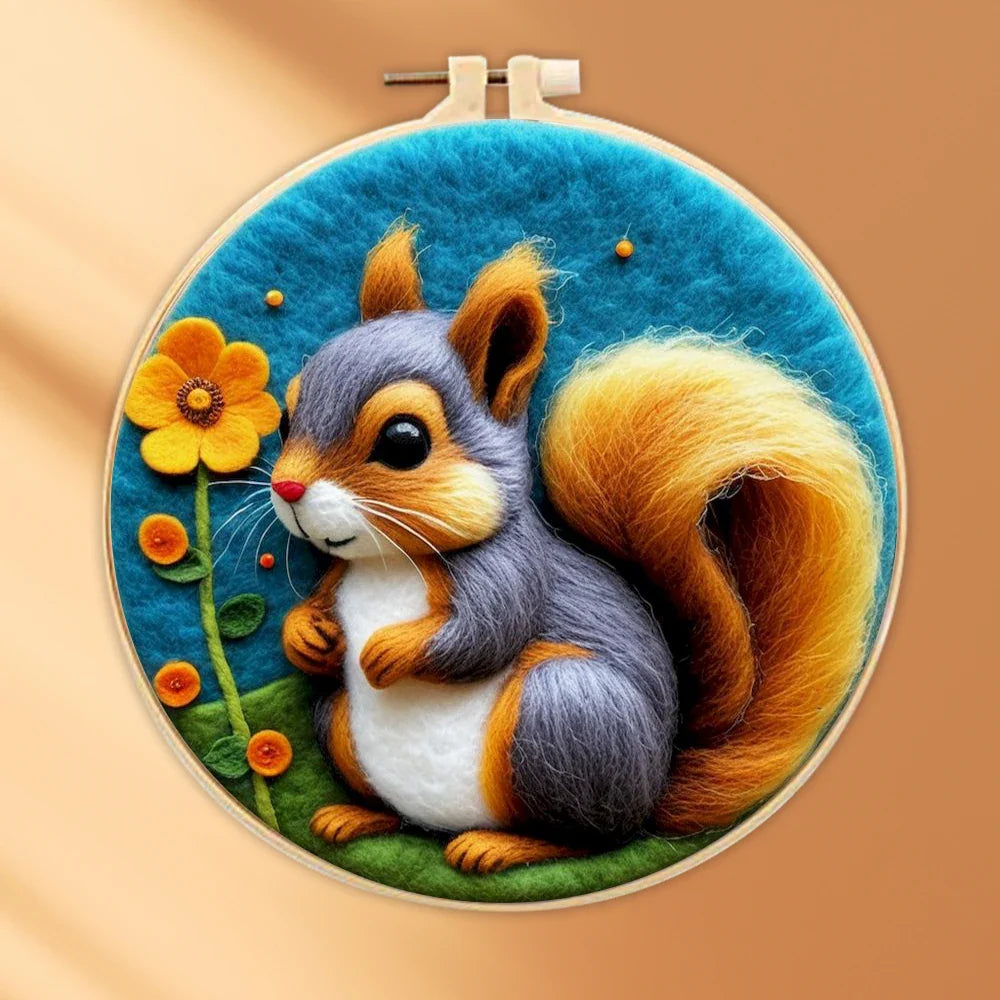 A person's hands holding a DIY felting kit with a pre-printed felt cloth depicting a white cat with orange spots, surrounded by colorful wool in the background.
