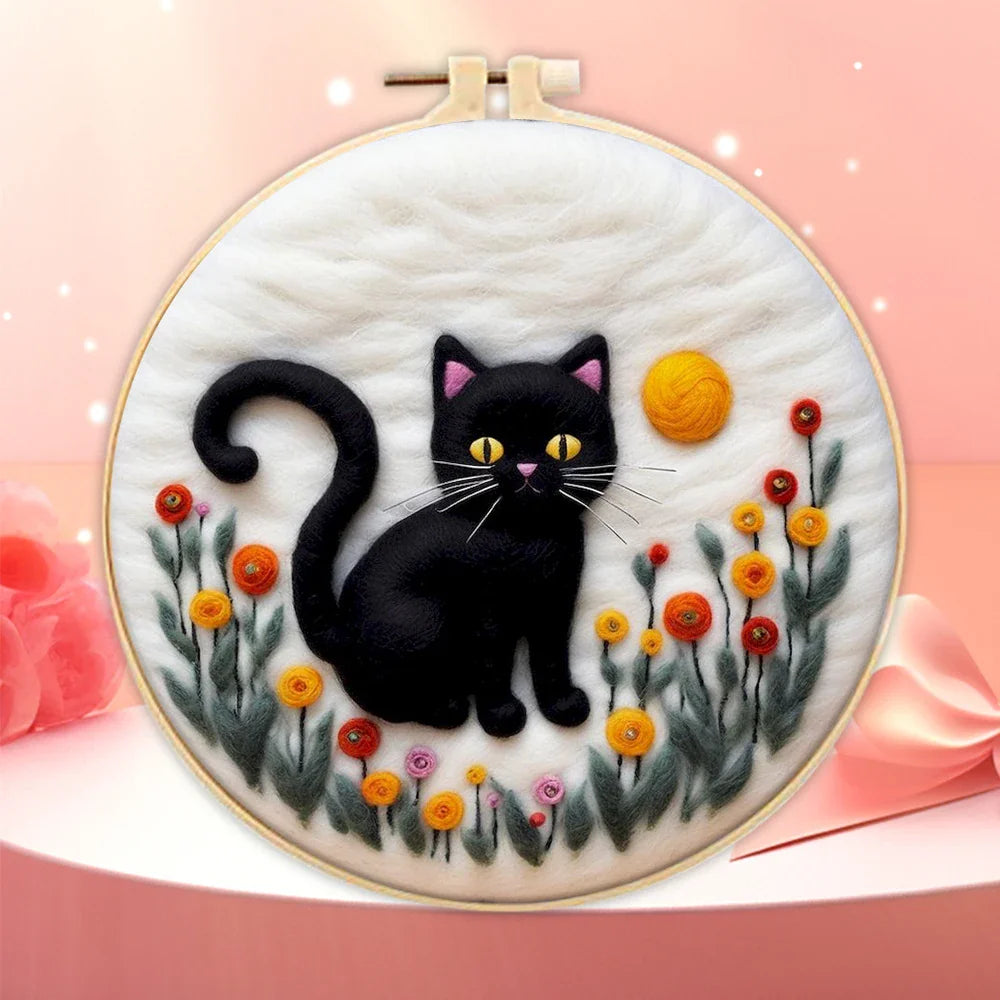 A person's hands holding a DIY felting kit with a pre-printed felt cloth depicting a white cat with orange spots, surrounded by colorful wool in the background.
