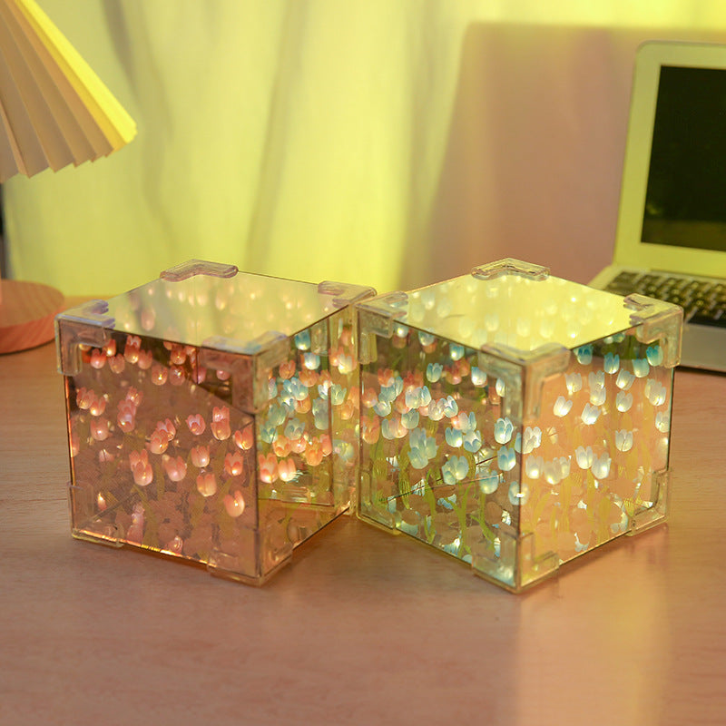 Two LED tulip cubes with multicolored lights, placed on a table, showcasing the floral design within the transparent material.
