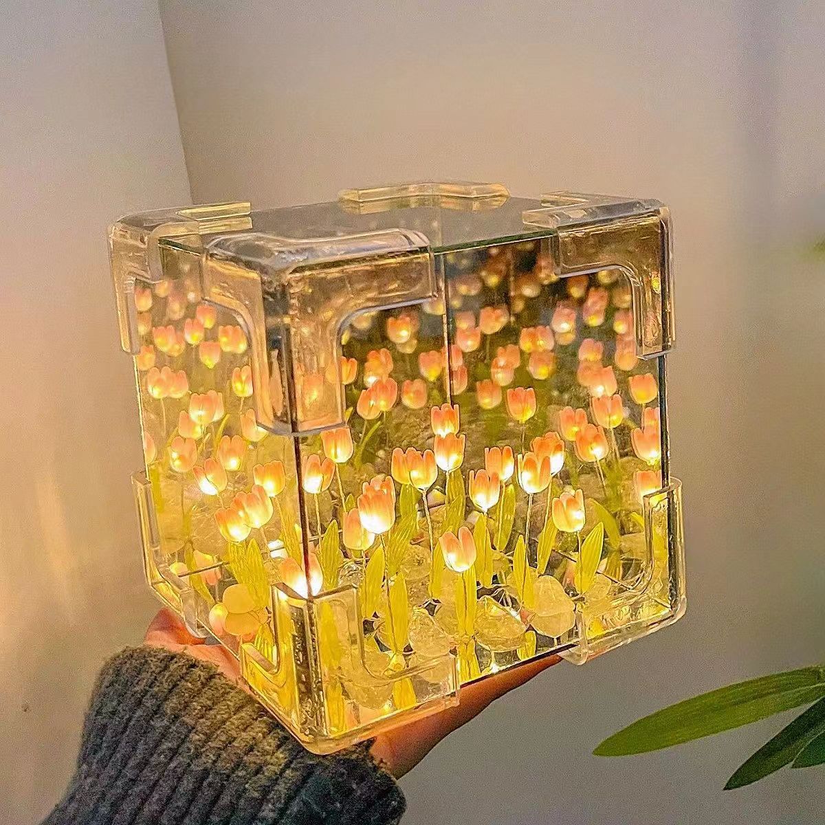 Two LED tulip cubes with multicolored lights, placed on a table, showcasing the floral design within the transparent material.