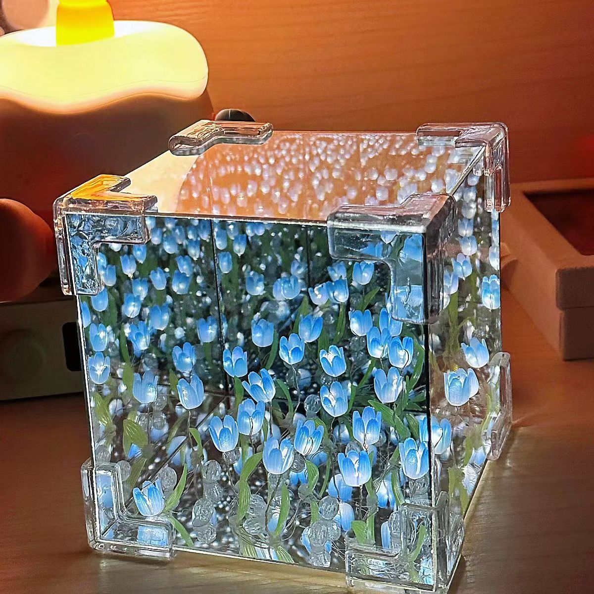 Two LED tulip cubes with multicolored lights, placed on a table, showcasing the floral design within the transparent material.