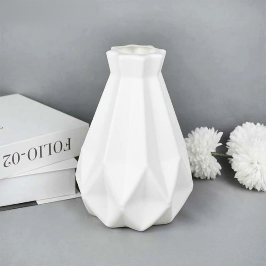 A collection of origami vases in white, pink, and turquoise colors displayed with flowers.