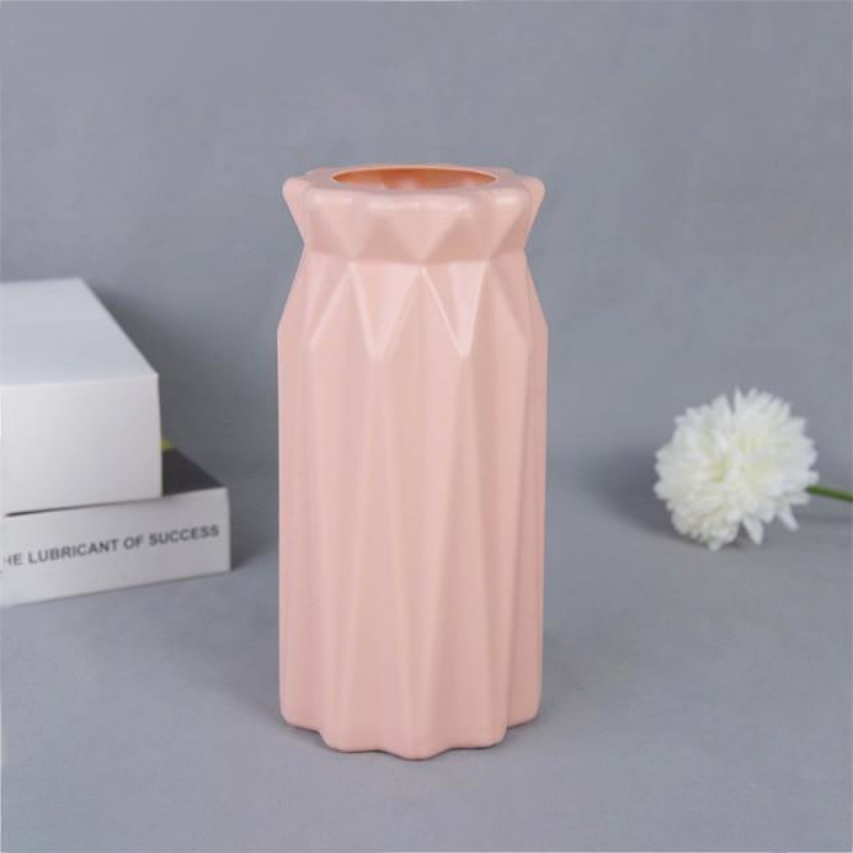 A collection of origami vases in white, pink, and turquoise colors displayed with flowers.