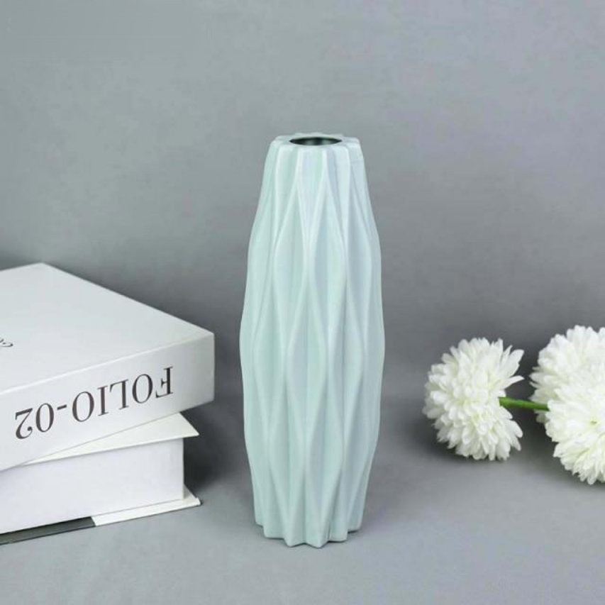 A collection of origami vases in white, pink, and turquoise colors displayed with flowers.