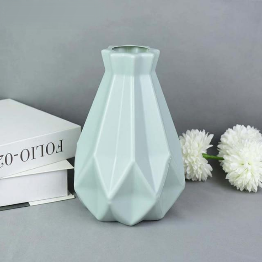 A collection of origami vases in white, pink, and turquoise colors displayed with flowers.
