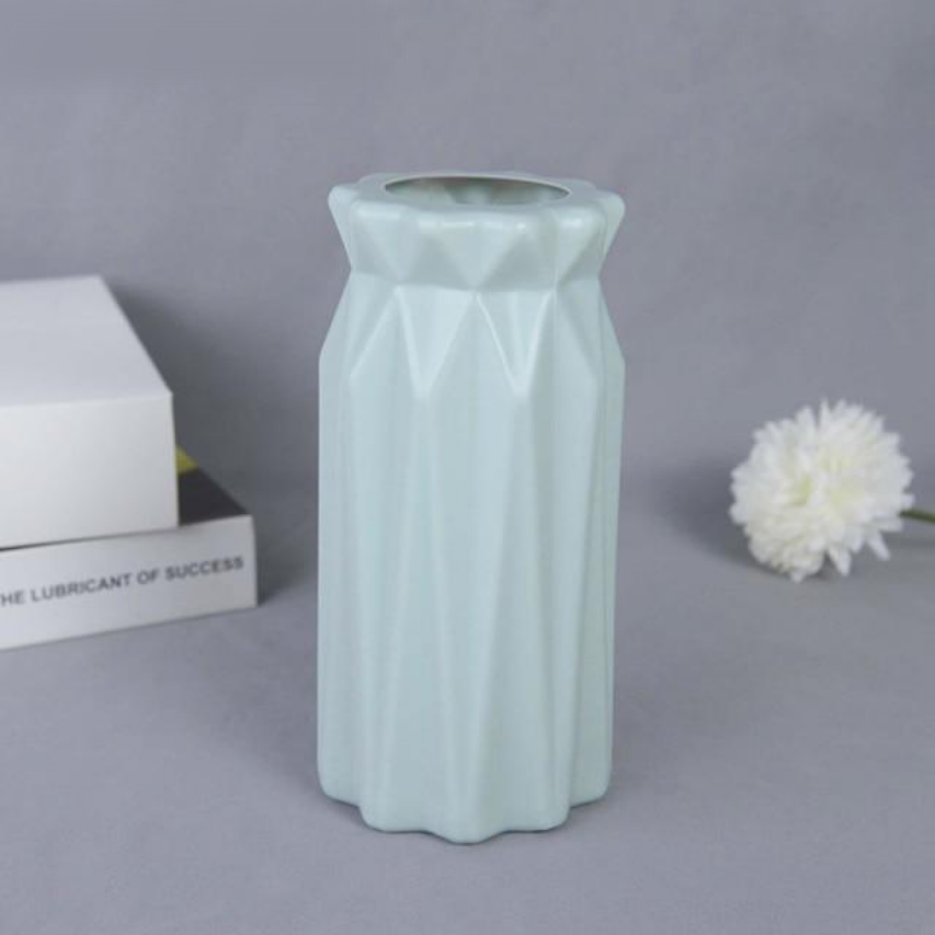 A collection of origami vases in white, pink, and turquoise colors displayed with flowers.