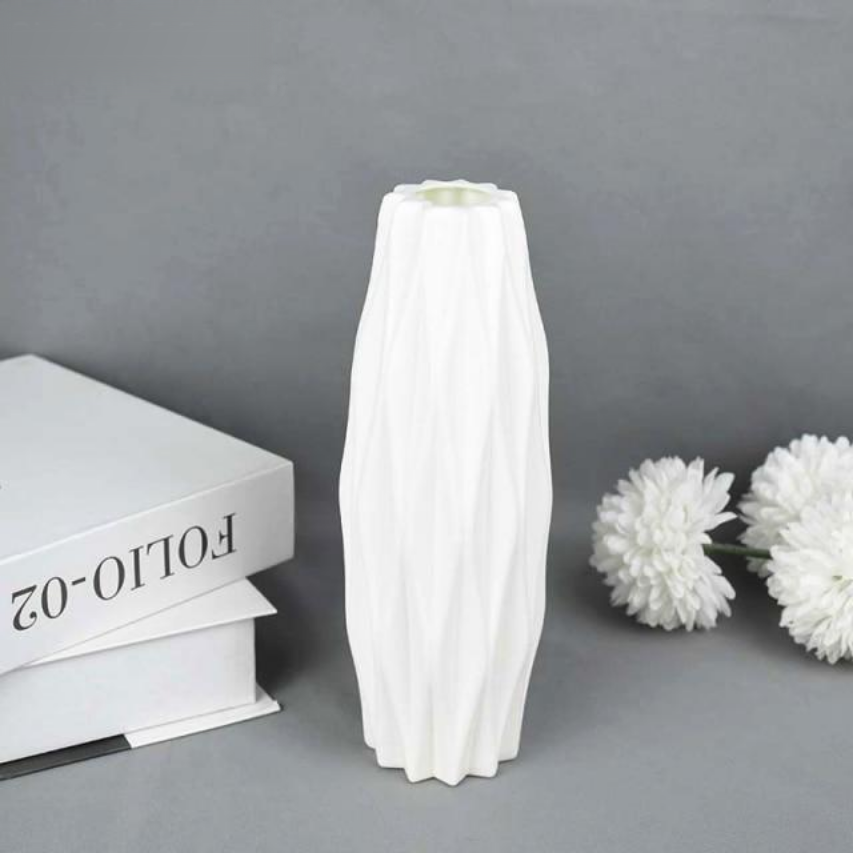A collection of origami vases in white, pink, and turquoise colors displayed with flowers.