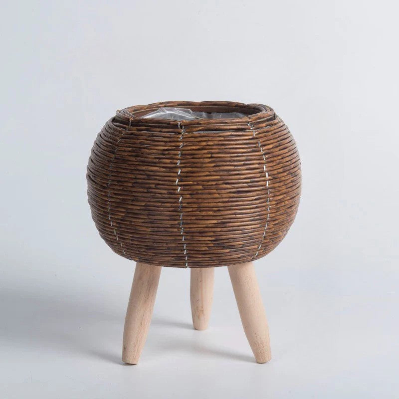 Wicker plant stand with wooden legs on a light gray background
