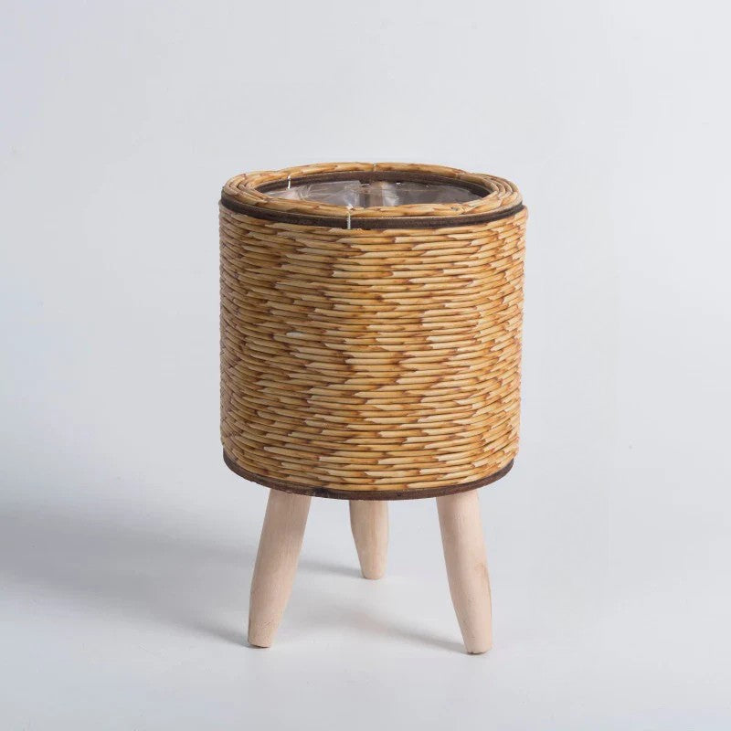 Wicker plant stand with wooden legs on a light gray background