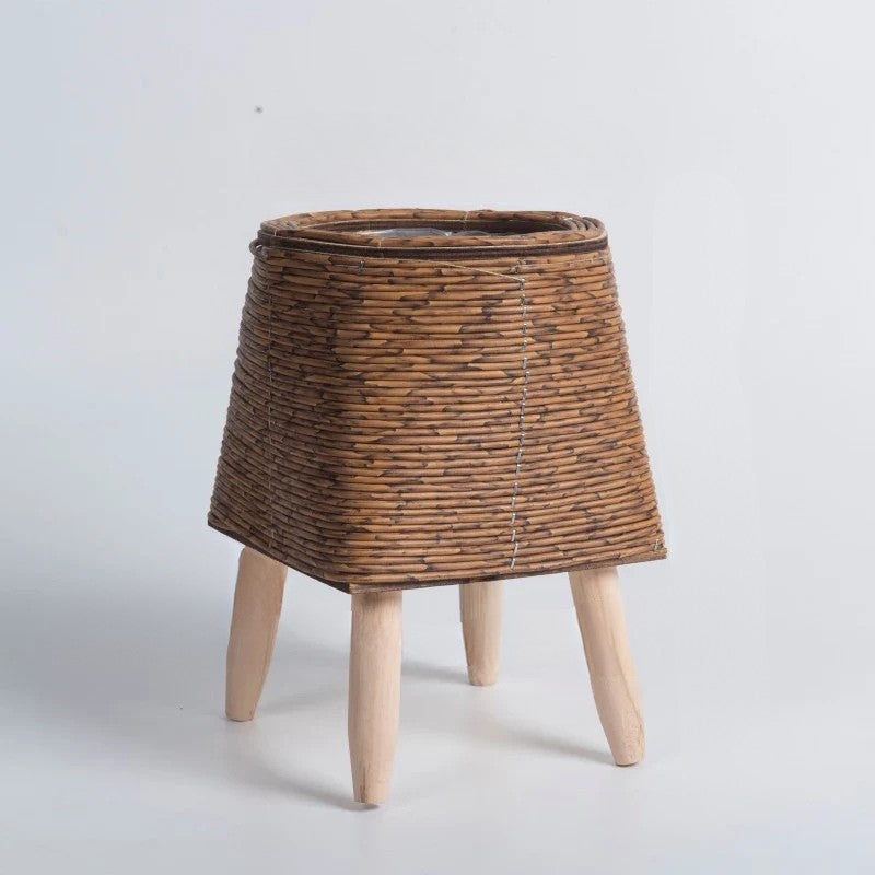 Wicker plant stand with wooden legs on a light gray background