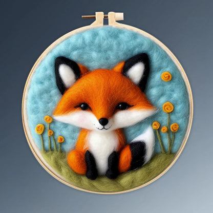 A person's hands holding a DIY felting kit with a pre-printed felt cloth depicting a white cat with orange spots, surrounded by colorful wool in the background.