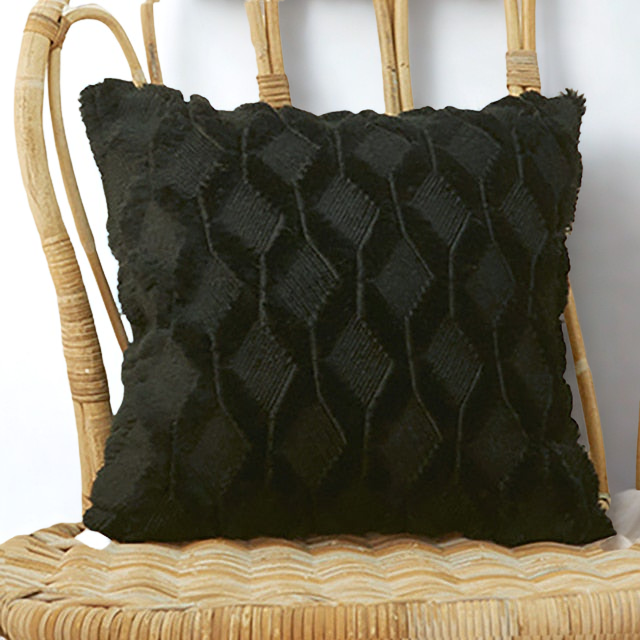 Black textured pillow on a wicker chair with a white background