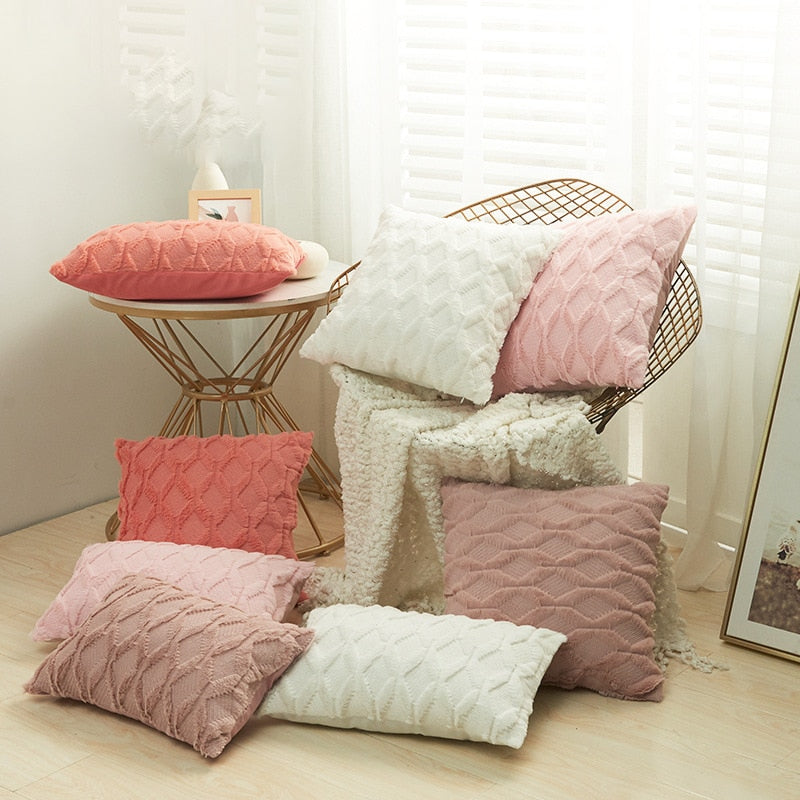 A collection of various colored cushion covers displayed on a wooden stool and the floor, with a few cushions inserted into the covers showcasing a textured design.