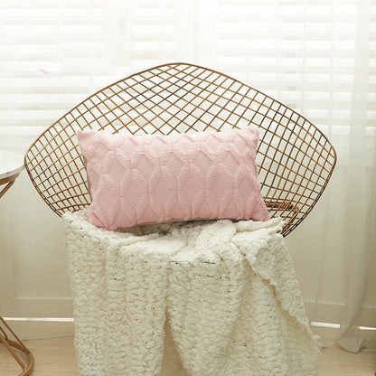 A collection of various colored cushion covers displayed on a wooden stool and the floor, with a few cushions inserted into the covers showcasing a textured design.