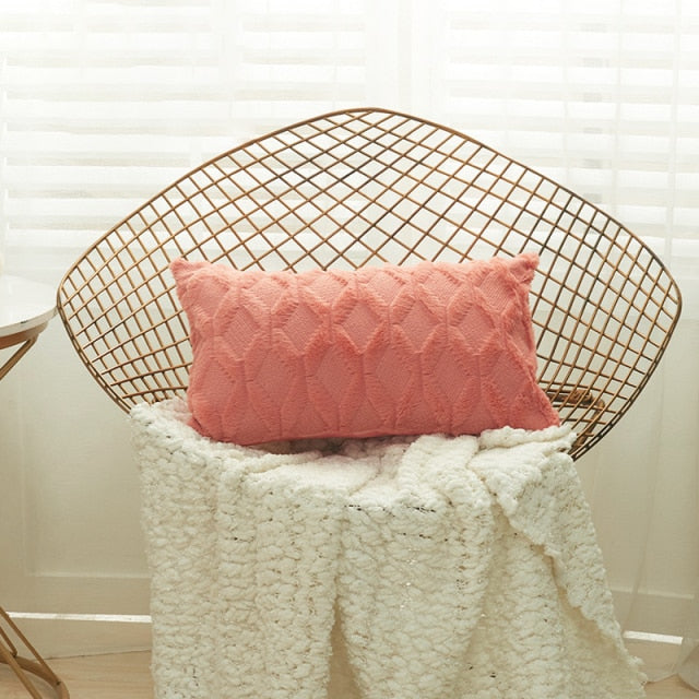 A collection of various colored cushion covers displayed on a wooden stool and the floor, with a few cushions inserted into the covers showcasing a textured design.