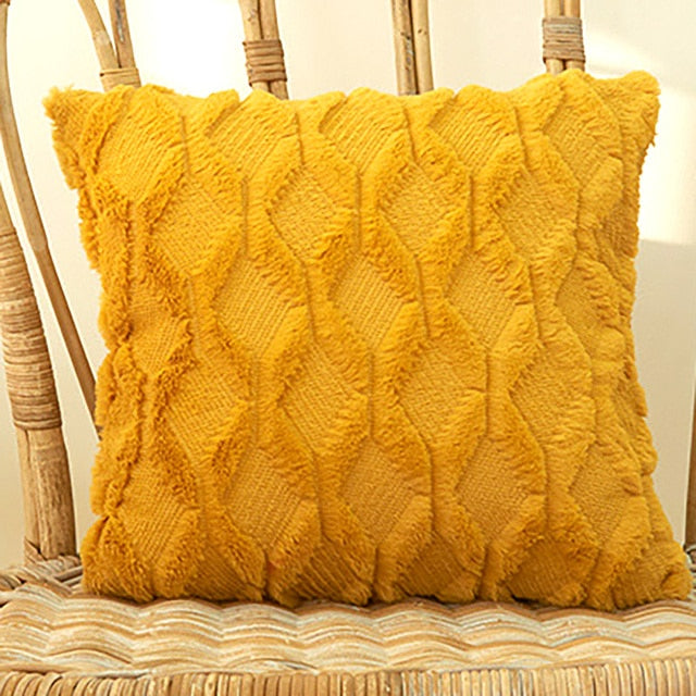 A collection of various colored cushion covers displayed on a wooden stool and the floor, with a few cushions inserted into the covers showcasing a textured design.