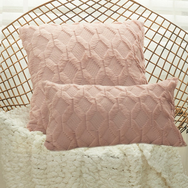 A collection of various colored cushion covers displayed on a wooden stool and the floor, with a few cushions inserted into the covers showcasing a textured design.