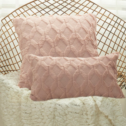 A collection of various colored cushion covers displayed on a wooden stool and the floor, with a few cushions inserted into the covers showcasing a textured design.