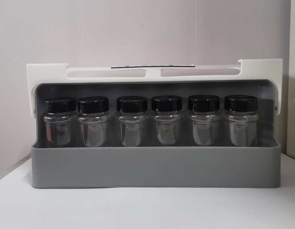 A foldable gray spice bottle holder organizer being mounted under a shelf, with various spice bottles inside.