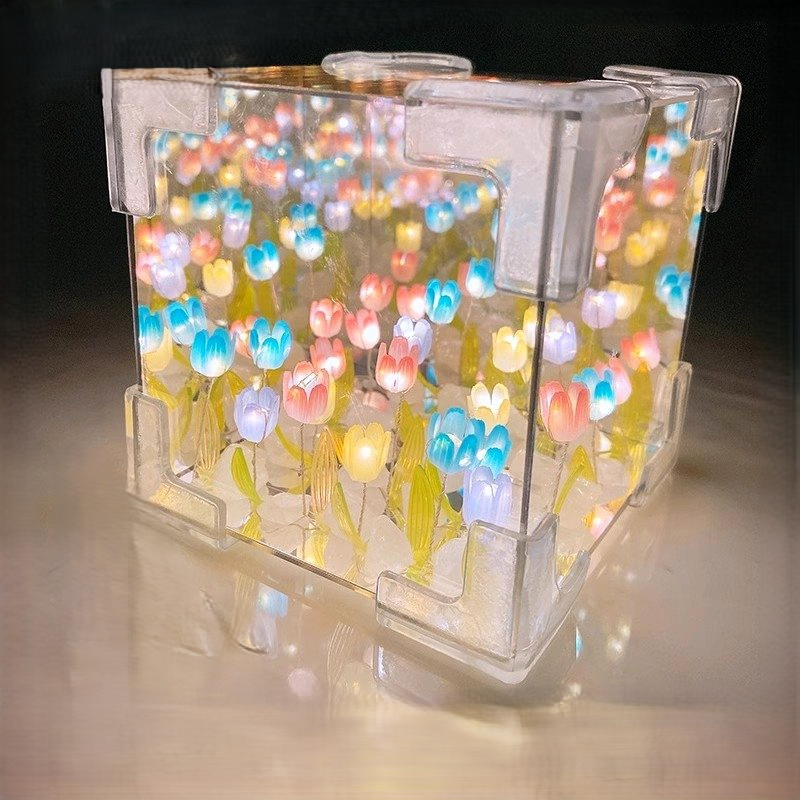 Two LED tulip cubes with multicolored lights, placed on a table, showcasing the floral design within the transparent material.