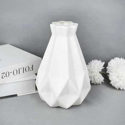 A collection of origami vases in white, pink, and turquoise colors displayed with flowers.