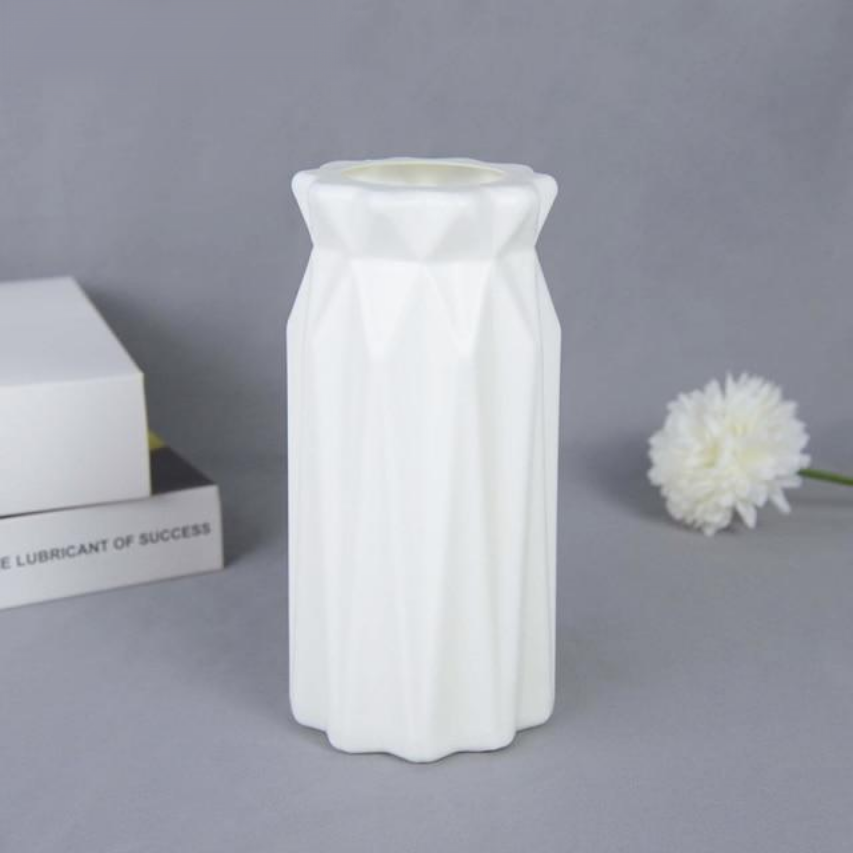 A collection of origami vases in white, pink, and turquoise colors displayed with flowers.