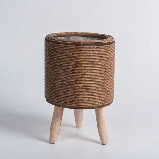 Wicker side table with wooden legs on a light gray background